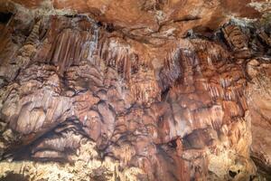 un cueva con un lote de marrón y blanco rock formaciones el rock formaciones son muy grande y el cueva es muy oscuro. foto