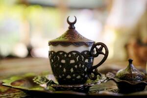 A cup with a crescent moon on top sits on a tray photo