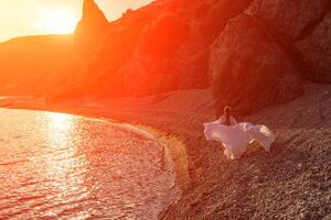 misterioso mujer silueta largo pelo camina en el playa Oceano agua, mar ninfa viento escucha a el ola. lanza arriba un largo blanco vestido, un adivinar puesta de sol. artístico foto desde el espalda sin un cara