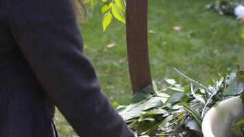 profesional florista trabajador decora festivo arco para ceremonial matrimonio registro. mujer instalando Boda decoración. decorador Decorar arco al aire libre Boda ceremonia con flores y verdor. video