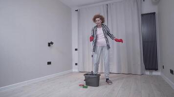 Jolly excited mature woman enjoying cleaning house, she dancing while washing floor. Happy elderly woman enjoying cleaning floors before moving to new apartment. Housework and housekeeping concept. video