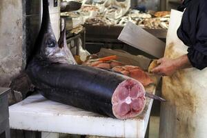 detalle de mano de un pescadero el cortar espadachín a Fresco pescado Mariscos a Ortigia Siracusa Sicilia pescado mercado Italia foto