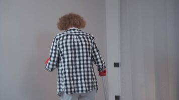 content mature femme au foyer en utilisant balai et seau de eau, en chantant et dansant tandis que Faire travaux ménagers dans vide chambre. de bonne humeur femme profiter travaux ménagers, ayant amusement tandis que nettoyage appartement avant en mouvement dans. video