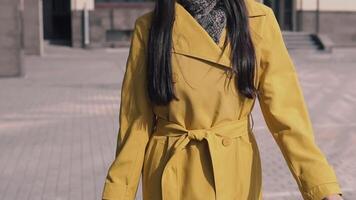beautiful girl in a yellow raincoat hat and glasses comes with luggage. slow motion video