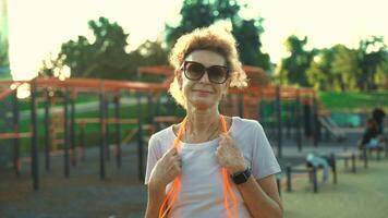 Aged woman using skipping rope. Middle age caucasian woman training using sport rope at street gym. Older woman with jumping rope ready for training. Mature woman relaxing after jumping training. video