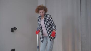 Senior woman is cleaning up before moving into a new apartment dancing and singing along to my floor with a mop. Excited woman enjoying housekeeping. People, housework and housekeeping concept. video