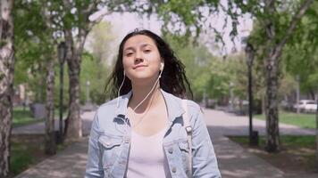 Happy funny girl in a denim jacket and a backpack walking down the street and dancing in a good mood video