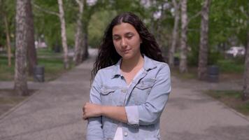 portrait de un attrayant Jeune fille avec longue cheveux dans une denim veste. magnifique fille permanent sur le rue. lent mouvement video