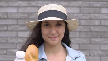 un joven hermosa mujer en un mezclilla chaqueta y sombrero es participación un paquete con Fresco sabroso productos el concepto de apropiado nutrición. compras, sano comida productos video