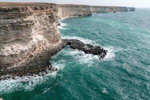 el Oceano es calma y el orilla es rocoso. el agua es un profundo azul color. el rocas son dentado y el olas son pequeño. el escena es pacífico y sereno. foto