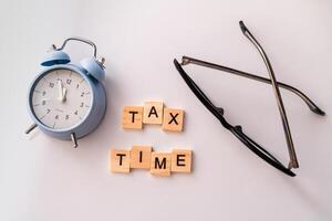 Close-up of alarm clock next to tax time concept on chalkboard photo