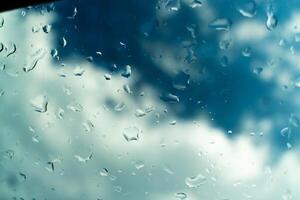 Water drops on glass against blue sky, rainy season concept. Window view background screensaver photo