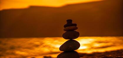 Pebble pyramid silhouette on the beach. Sunset with sea in the background. Zen stones on the sea beach concept, tranquility, balance. Selective focus photo