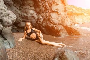 mujer traje de baño mar. atractivo rubia mujer en un negro traje de baño disfrutando el mar aire en el costa alrededor el rocas viaje y vacaciones concepto. foto