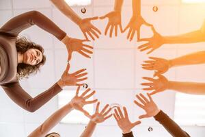 Team of people holding hands. Group of happy young women holding hands. Bottom view, low angle shot of human hands. Friendship and unity concept photo