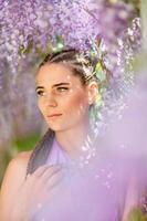 Woman wisteria lilac dress. Thoughtful happy mature woman in purple dress surrounded by chinese wisteria photo