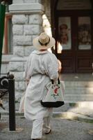 A woman in a hat in a white outfit with a bag walks around the Livadia Palace photo
