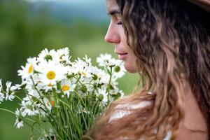 un de edad mediana mujer sostiene un grande ramo de flores de margaritas en su manos. flores silvestres para Felicidades foto