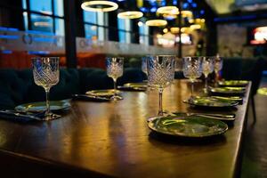 A table with a number of wine glasses and plates. The table is set for a meal. Scene is elegant and sophisticated. photo