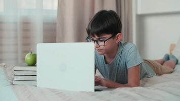 Home Isolation, Online Learning, Remote Work, New Education. A schoolboy during online learning lies on a bed at home video