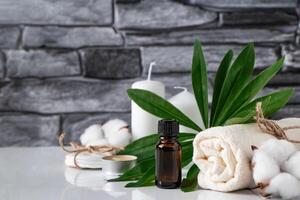 Essential oil, towel and candles on gray stone background. Spa wellness accessories and cosmetics. photo