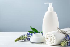 Cosmetic bottle with lotion and lupine flowers on gray background. photo