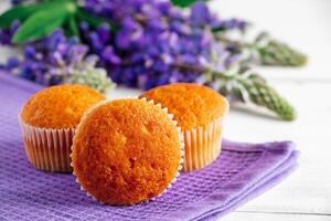 Delicious muffins and purple lupine flowers on white wooden background. photo