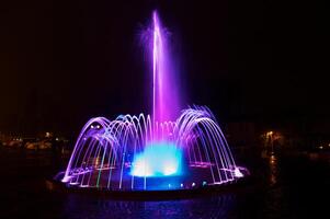 Coloured water fountain at night photo