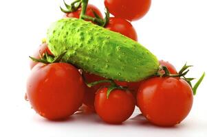 Ripe tomatoes on a branch and cucumber on a white background photo