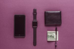 Business concept. Top view of dollars, watch, smartphone on color background photo