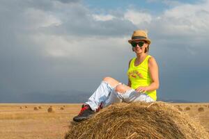 hermosa joven niña en un campo con Paja en un antecedentes de arco iris foto