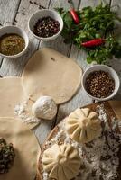 Close up to Caucasian khinkali dumplings dish served on plate. Background with ingredients and scattered spices photo