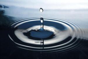 la gota de agua redonda y transparente, cae hacia abajo foto