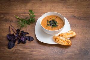 Tomato, red pepper soup, sauce with olive oil, rosemary and smoked paprika on a wooden background photo