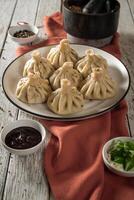 Close up to Caucasian khinkali dumplings dish served on plate. Background with ingredients and scattered spices photo