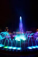 Coloured water fountain at night photo