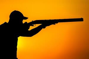 Silhouette of people with guns at sunset photo