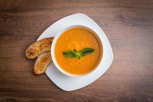 Lentil soup with spices, herbs, bread in a rustic metal saucepan and bowls, wood backdrop, top view. photo