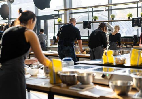 Culinary class. Back view of the process of cooking. Different unrecognizable people in gray apronsthe in the kitchen learn to cook photo