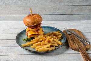 Tempting Burger on a wooden table with crispy fries and fresh vegetables. photo