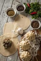 Close up to Caucasian khinkali dumplings dish served on plate. Background with ingredients and scattered spices photo