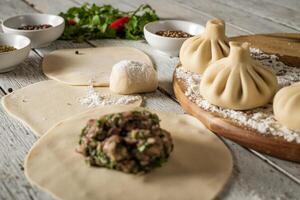 Close up to Caucasian khinkali dumplings dish served on plate. Background with ingredients and scattered spices photo