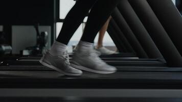 Close up sport shoes sneakers female male legs feet motion run jog on treadmill workout in gym jogging exercise cardio running couple runners joggers woman and man training in fitness club side view video