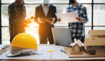 ingeniero escritorio con objeto papel y tableta con borroso ingeniero trabajo en equipo trabajo duro a consulta acerca de su edificio proyecto.en oficina foto