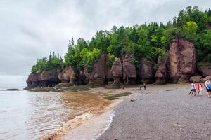 Bay of Fundy, Canada - August 12, 2015-People walk on the bottom of the Bay of Fundy as the tide is out on an overcast day photo