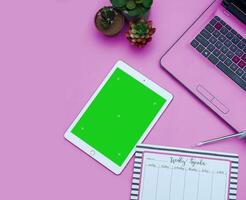 Top view of a streamlined work-from-home workspace with essential gadgets and a green screen setup. This minimalist arrangement is perfect for efficient remote work, virtual meetings, creatives. photo