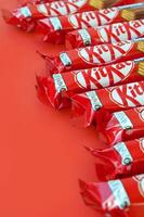 Kit Kat chocolate bars in red wrapping lies on yellow background is now produced globally by Nestle. Have a break - have a Kit Kat photo