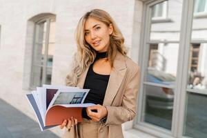 Sucsessful blond business woman posing in stylish suit outdoor. Holding  bdesigner catalogs. photo