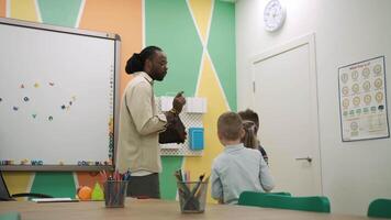 un africano americano profesor y un grupo de niños son estudiando frutas y animales en el aula.escuela para niños, enseñando adolescentes, ganancia conocimiento, aprender el idioma. video