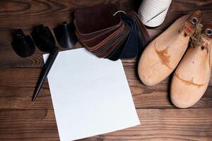 Leather samples for shoes and wooden shoe last on dark wooden table. photo